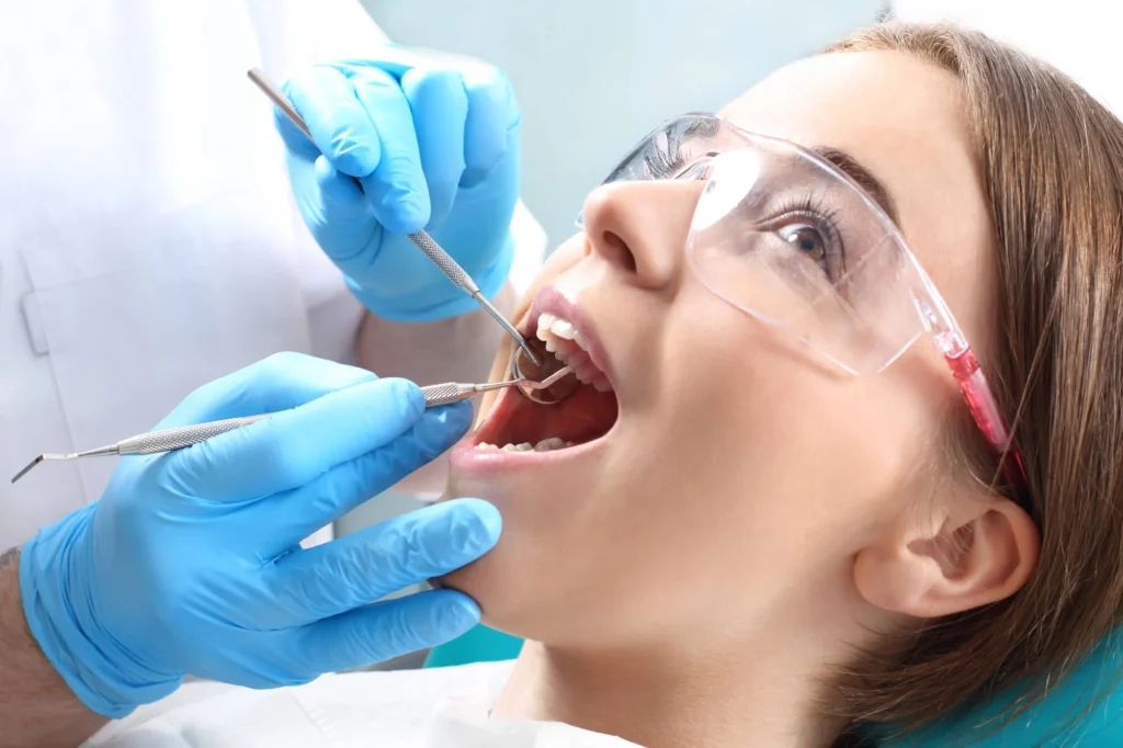 Dentist examining patient’s teeth with tools dentist in Lincoln Square