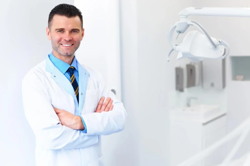 Smiling dentist standing in bright clinic, emergency dental clinic near you