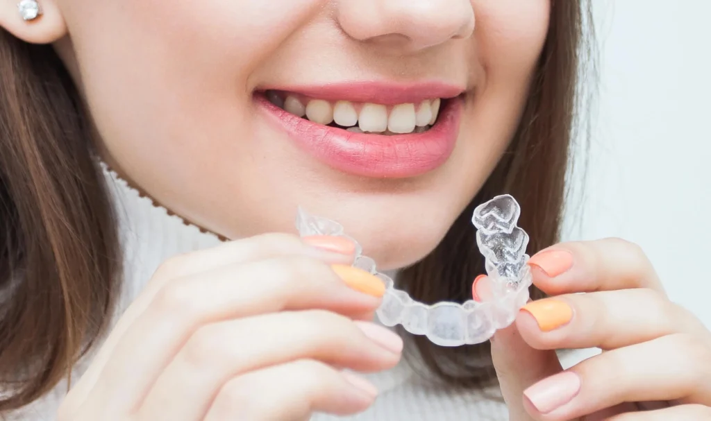 Woman holding clear aligners for teeth straightening invisalign in Mount Holly